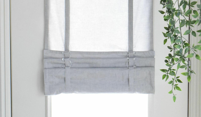 With a tiered tumble shade in Charlotte, you can block sun glare all year round. Gray rolled tumble shade on a glass door