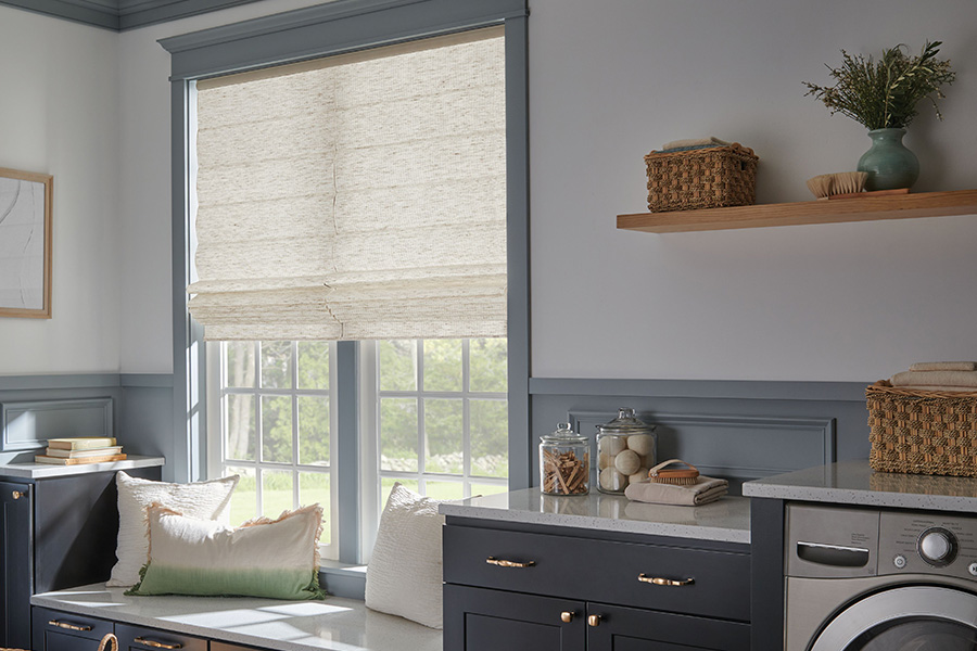 White window shade on a window in a blue laundry room