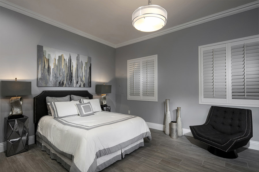 Create the perfect sleeping space with Polywood shutters that block even the brightest light. Closed white Polywood shutters on windows in a gray bedroom