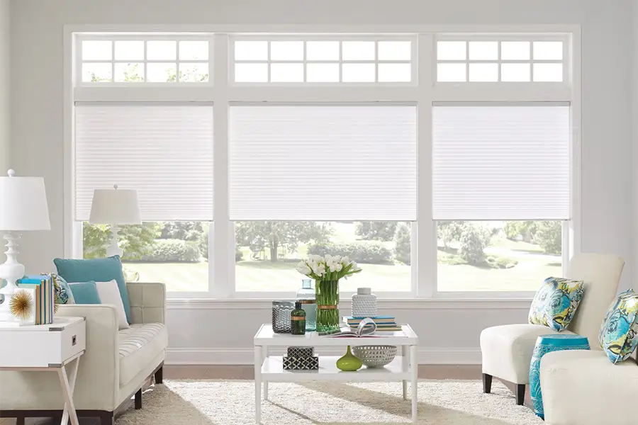 Insulating cellular shades can help keep cold air and hot UV rays from entering your Charlotte home. White cellular shades on windows in a white living room
